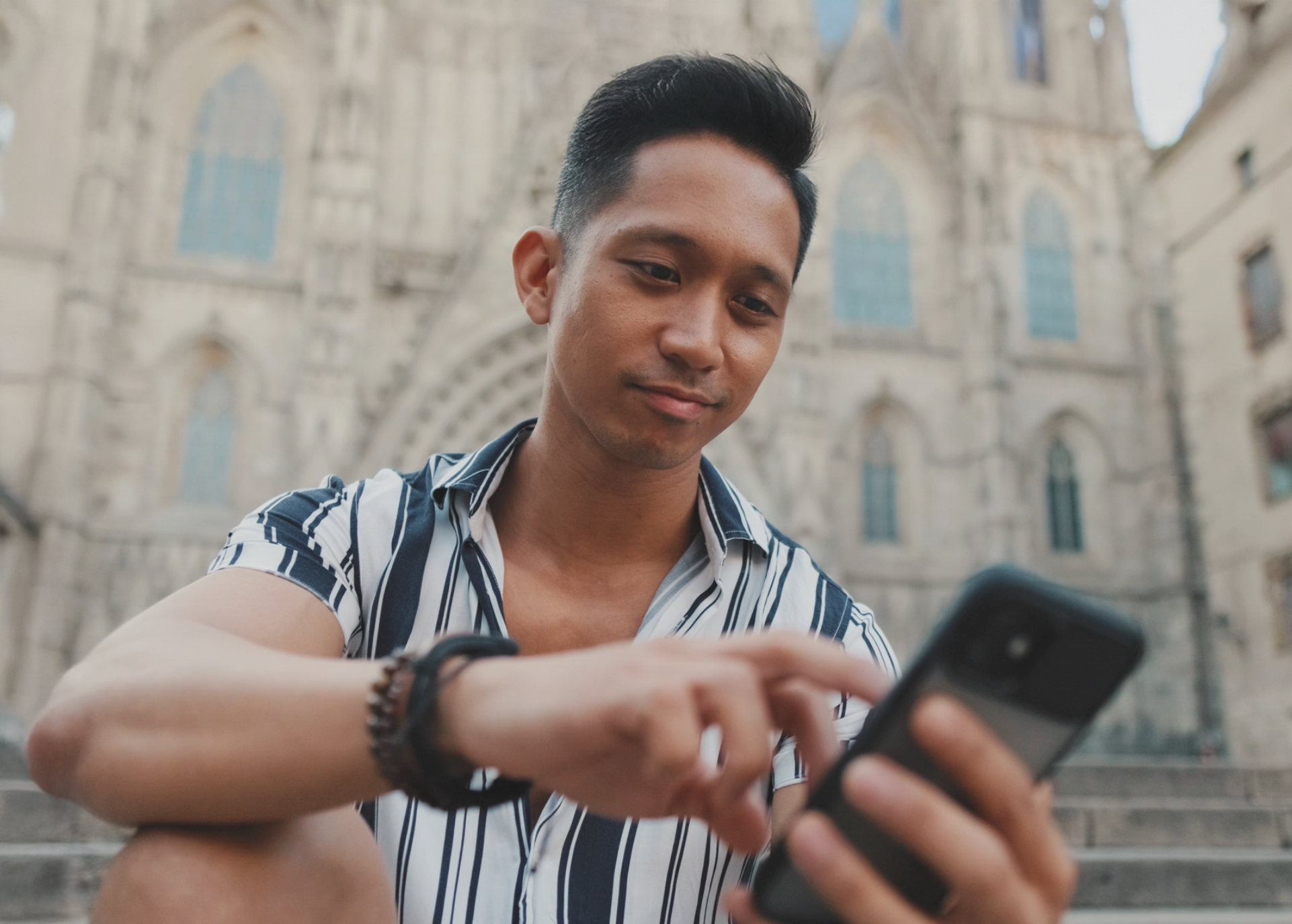 A young man using his phone outside a cathedral
