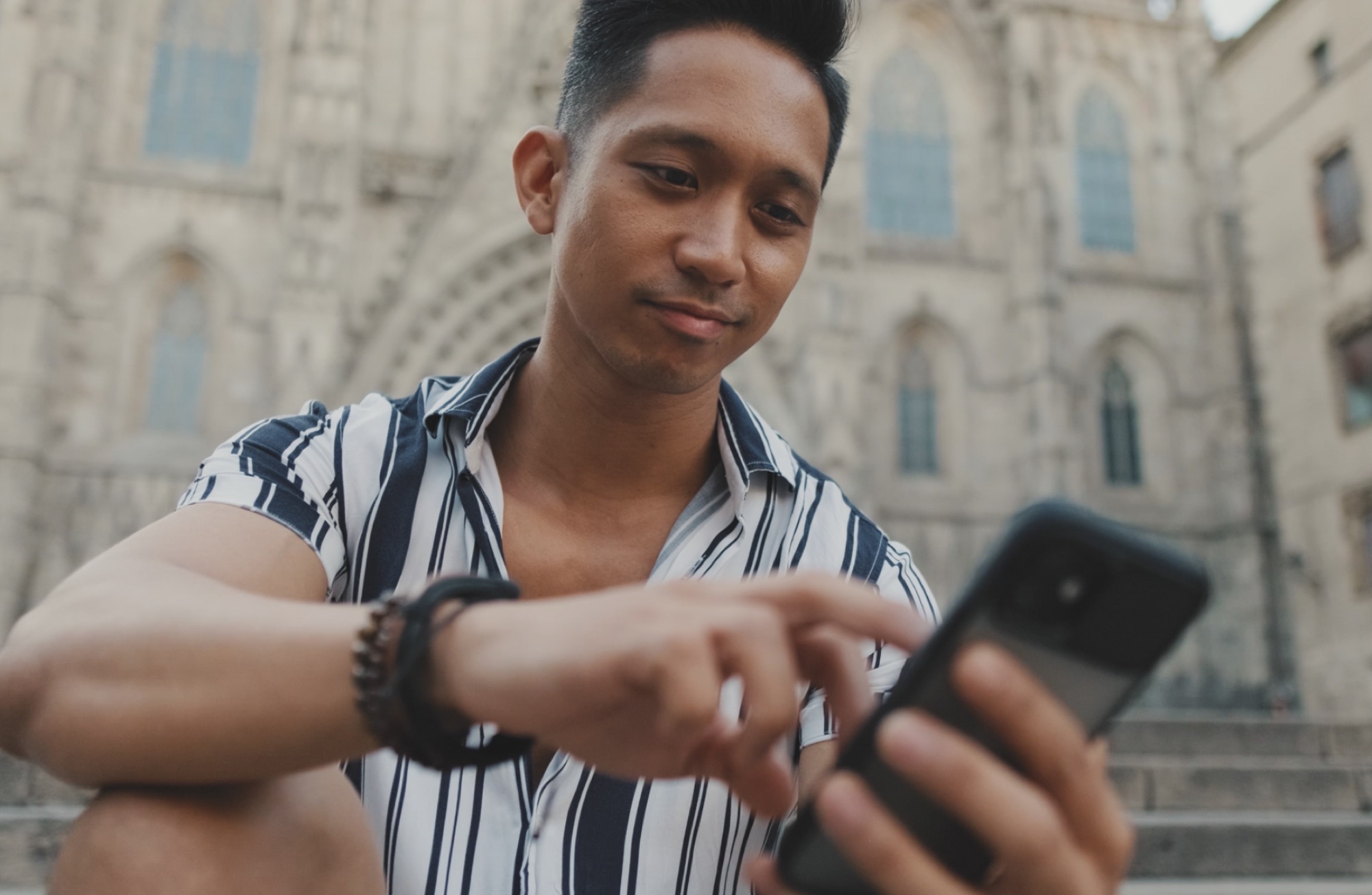 A young man using his phone outside a cathedral